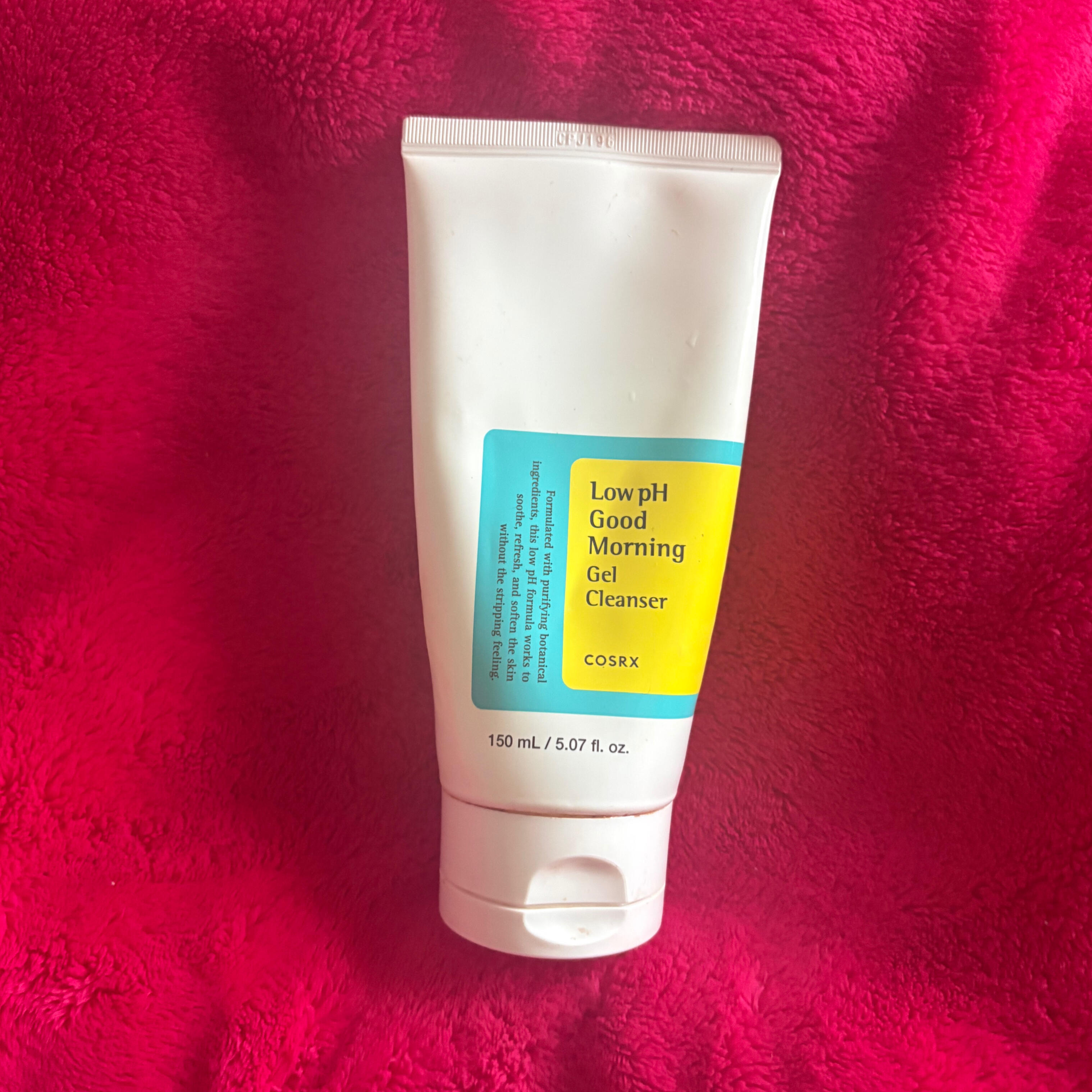 COSRX Low pH Good Morning Gel Cleanser A photo of the 5 oz white tube of cosrx low ph good morning gel cleanser with a bright blue and yellow label on it. Taken on a pink background.